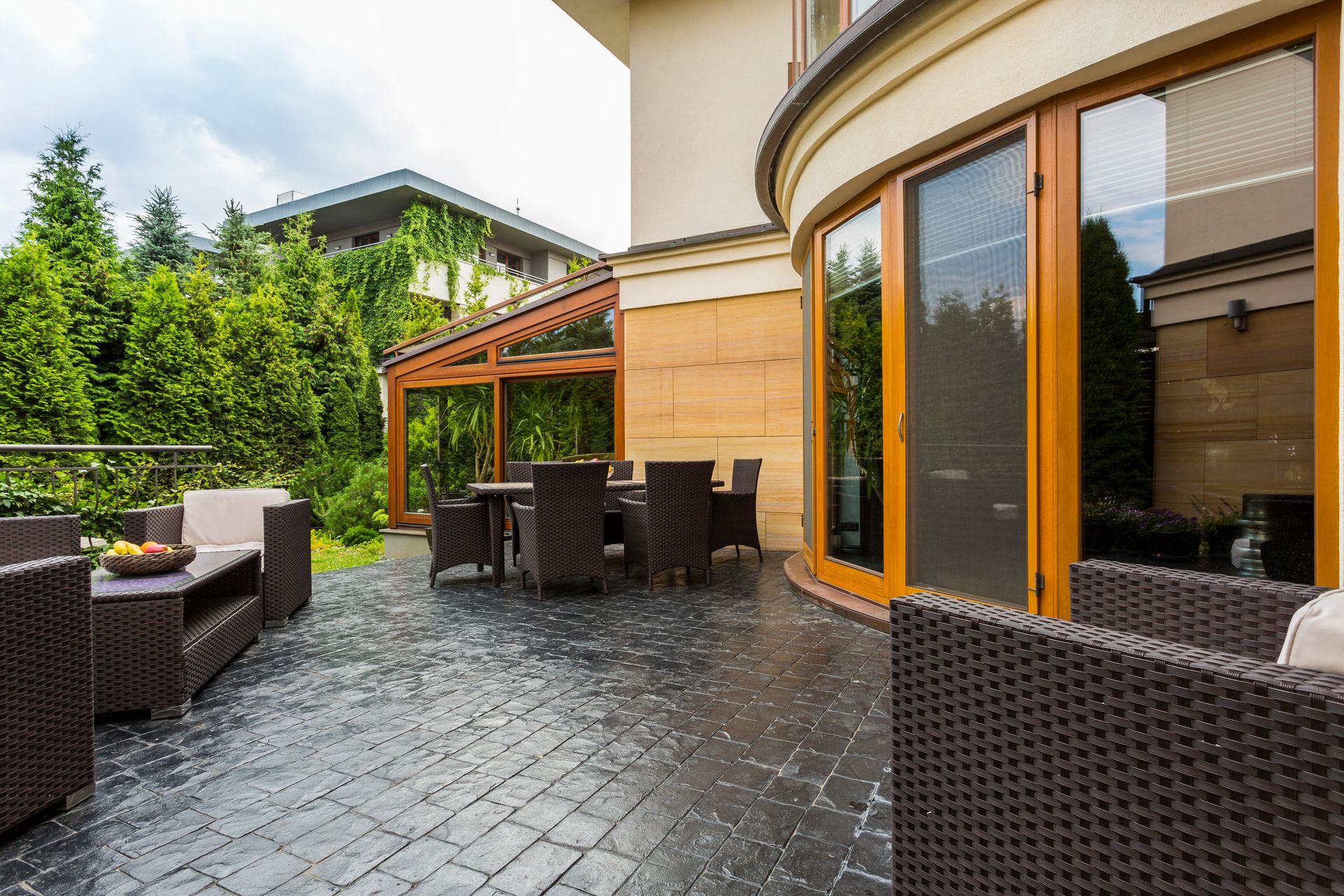 Outdoor patio with wicker seating, pergola, and large glass doors beside a house
