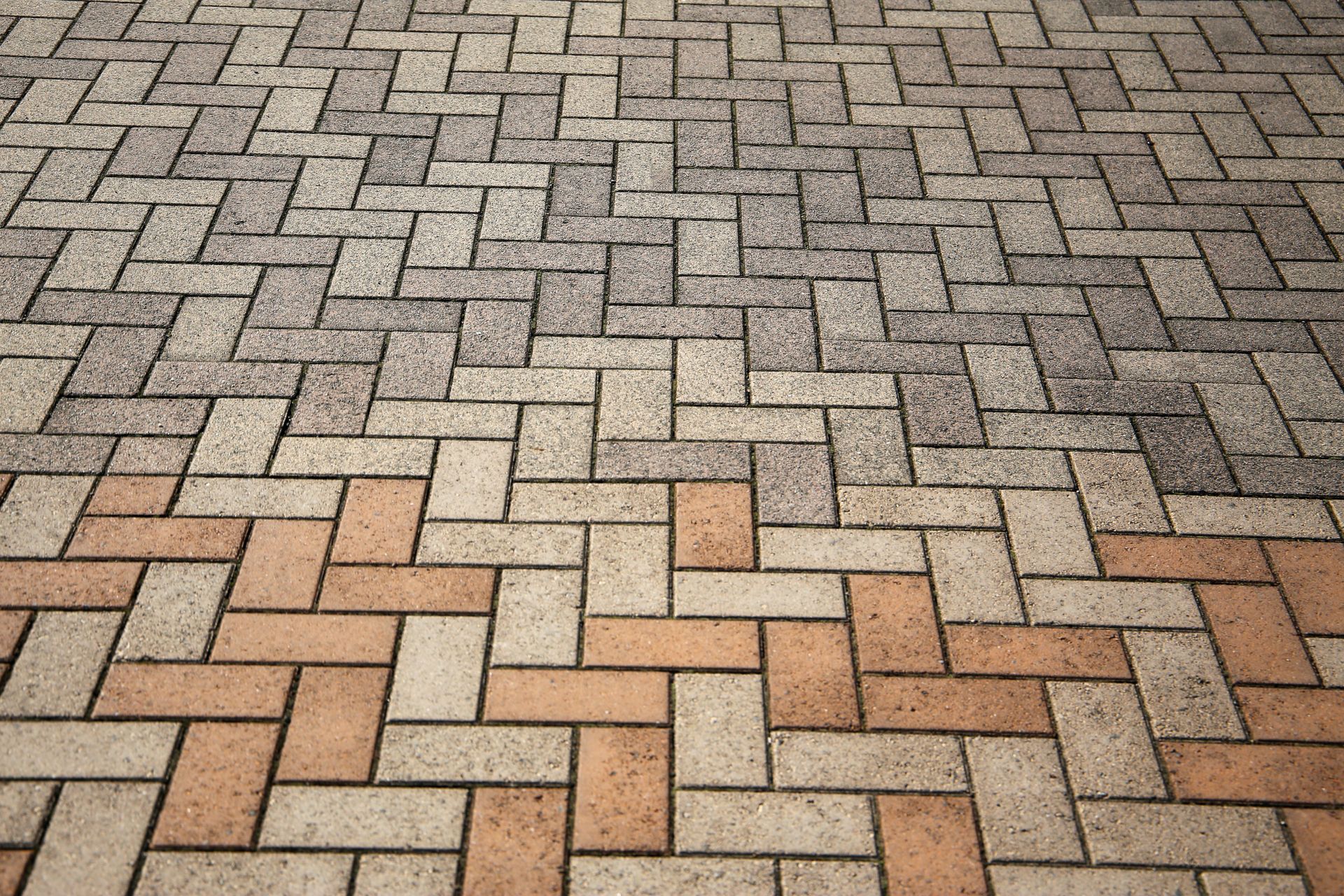 Patterned brick pavement in gray and tan tones with herringbone-style blocks