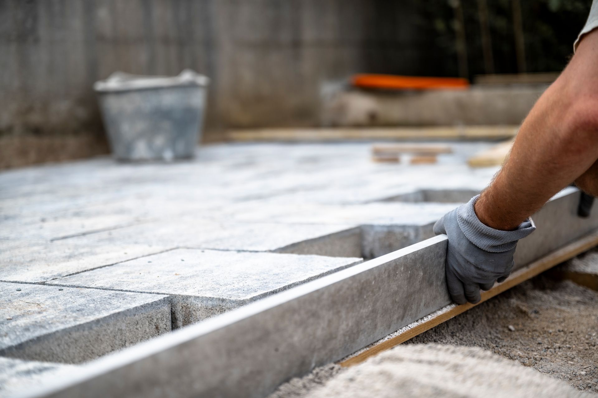 Worker smoothing wet concrete along a curb with a metal trowel