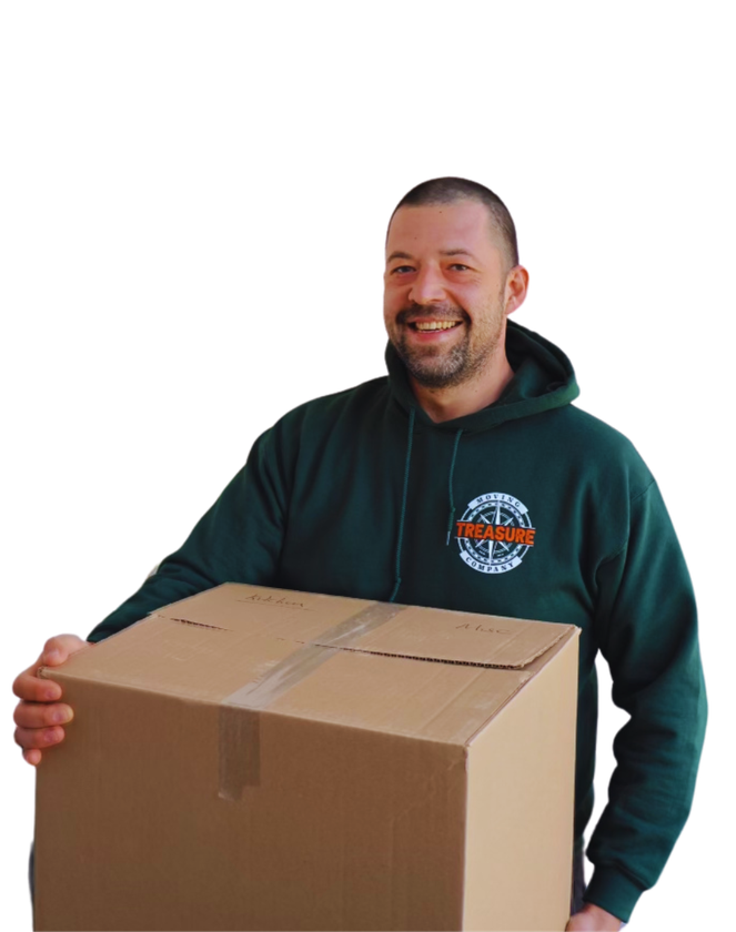Man in green hoodie holding a cardboard box, smiling.