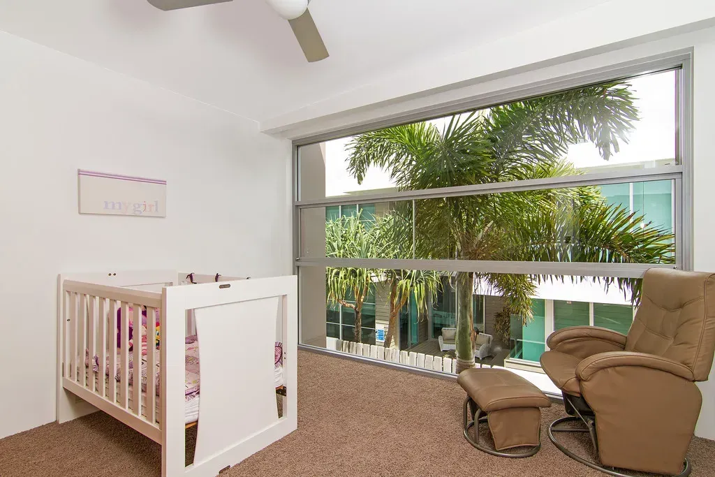 A nursery with a crib and a rocking chair — Maryborough Bay Glass & Aluminium in Maryborough, QLD