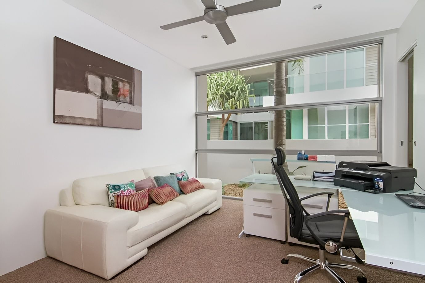 A living room with a couch and a desk with a printer — Maryborough Bay Glass & Aluminium in Maryborough, QLD