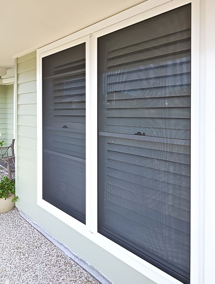 Two white-framed windows with black screens on a light green wall. The windows are set in a building's exterior. — Maryborough Bay Glass & Aluminium in Howard, QLD