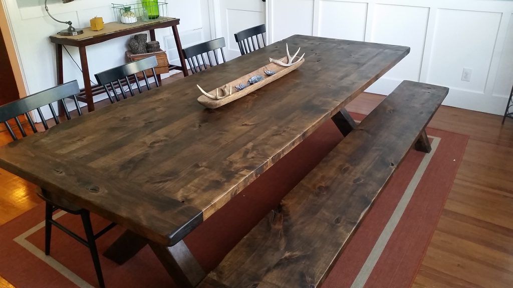 A wooden table with a bench and chairs in a dining room.
