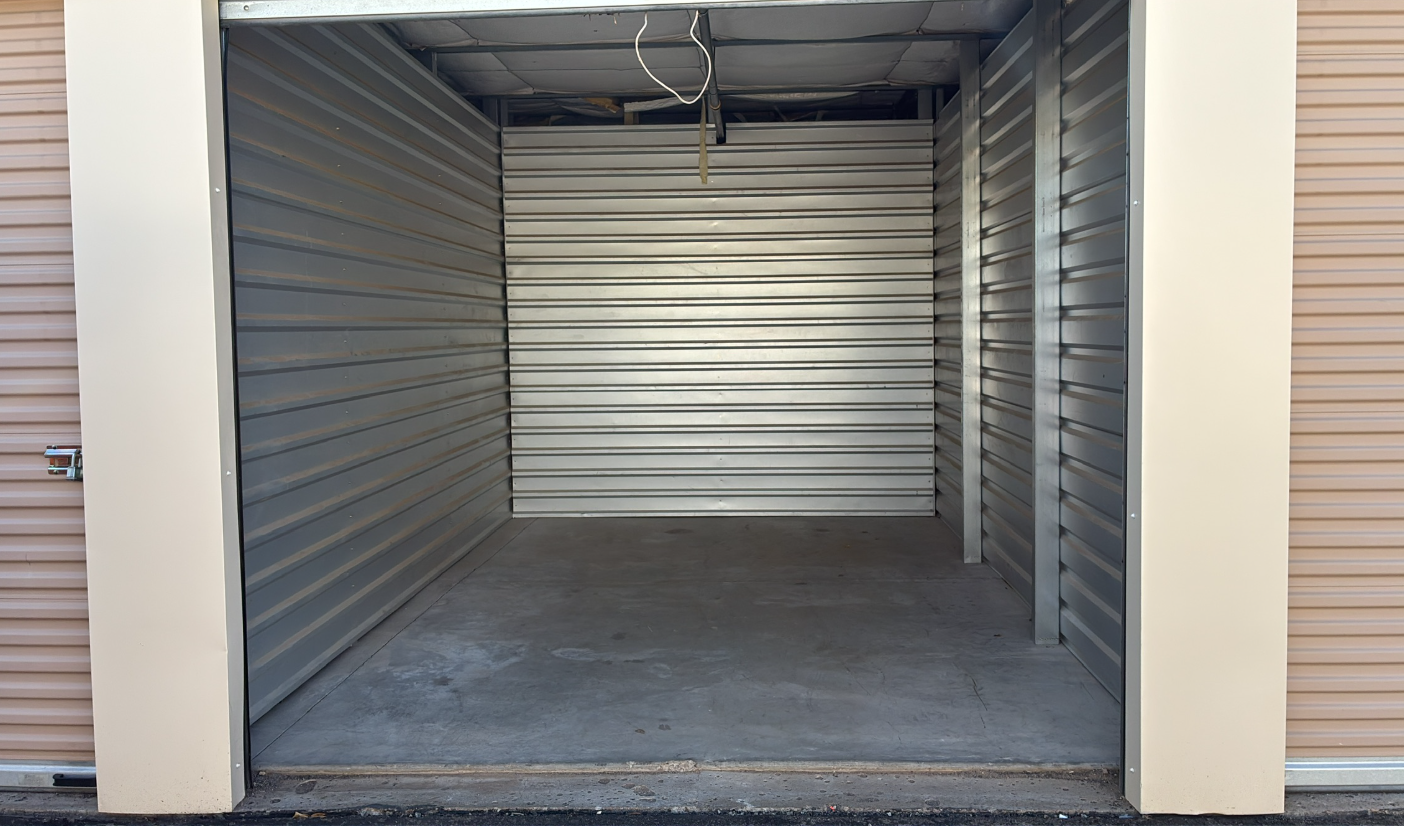 Empty storage unit with open roll-up door and corrugated metal walls