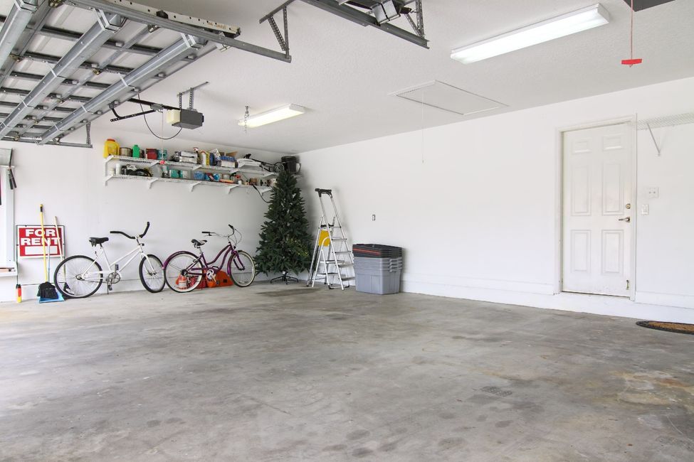 Empty garage with bicycles, a small Christmas tree, and a white door on the right.