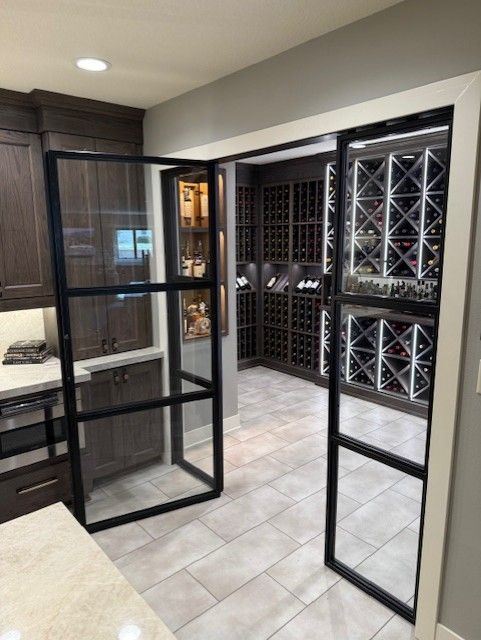 Open glass pantry door beside built-in wine storage in a modern kitchen