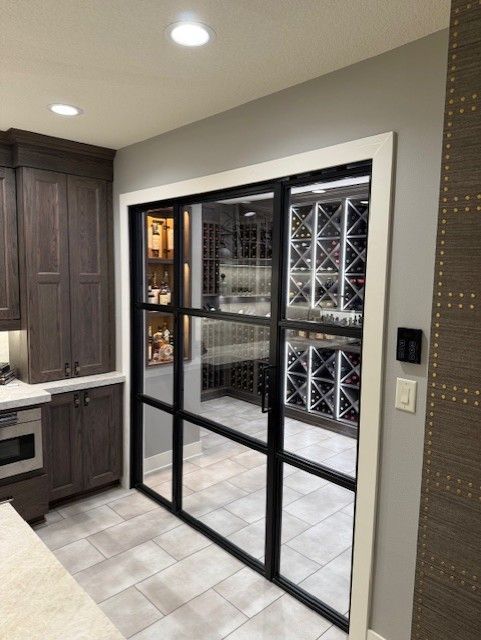 Modern kitchen with a black-framed glass wine room and tiled floor