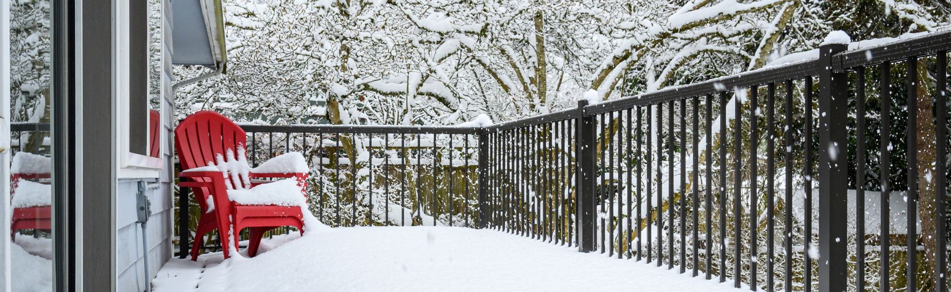 Snow-covered black metal custom railings on a home deck