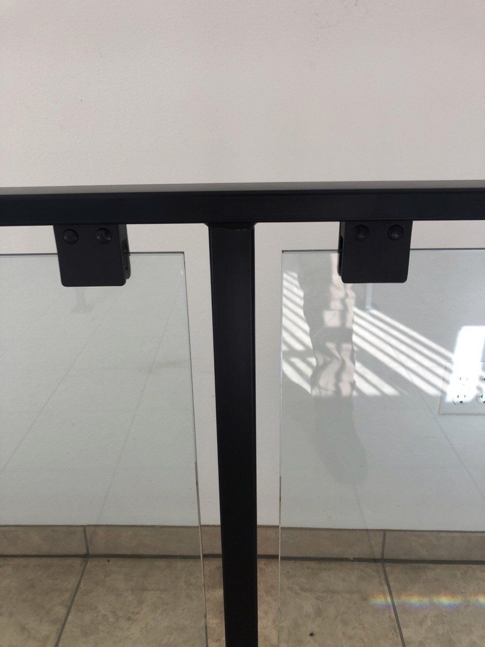 Glass office doors with black metal frames and floor reflections on a tiled floor