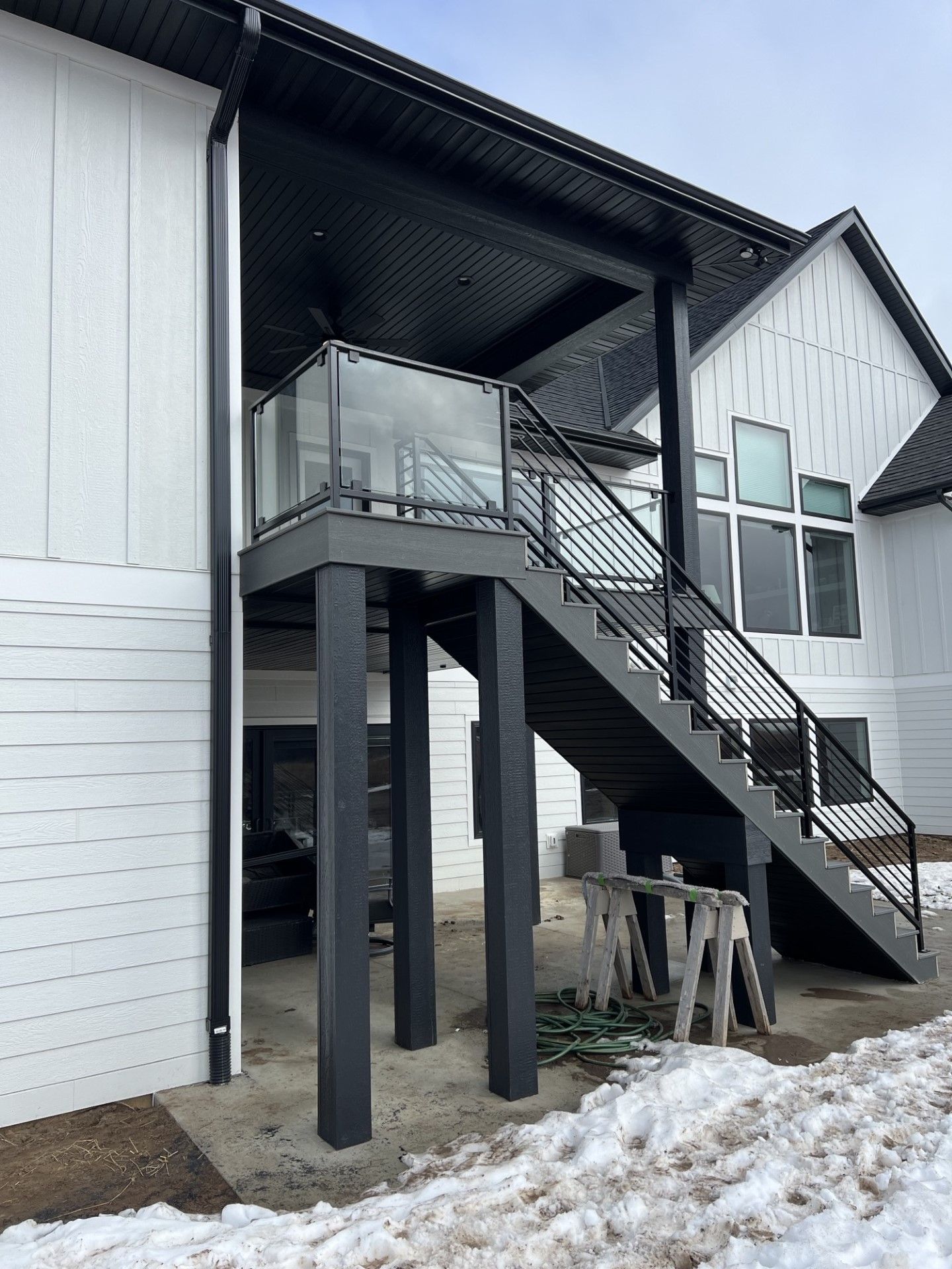 Exterior staircase and elevated deck on a white building with black posts and snowy ground below