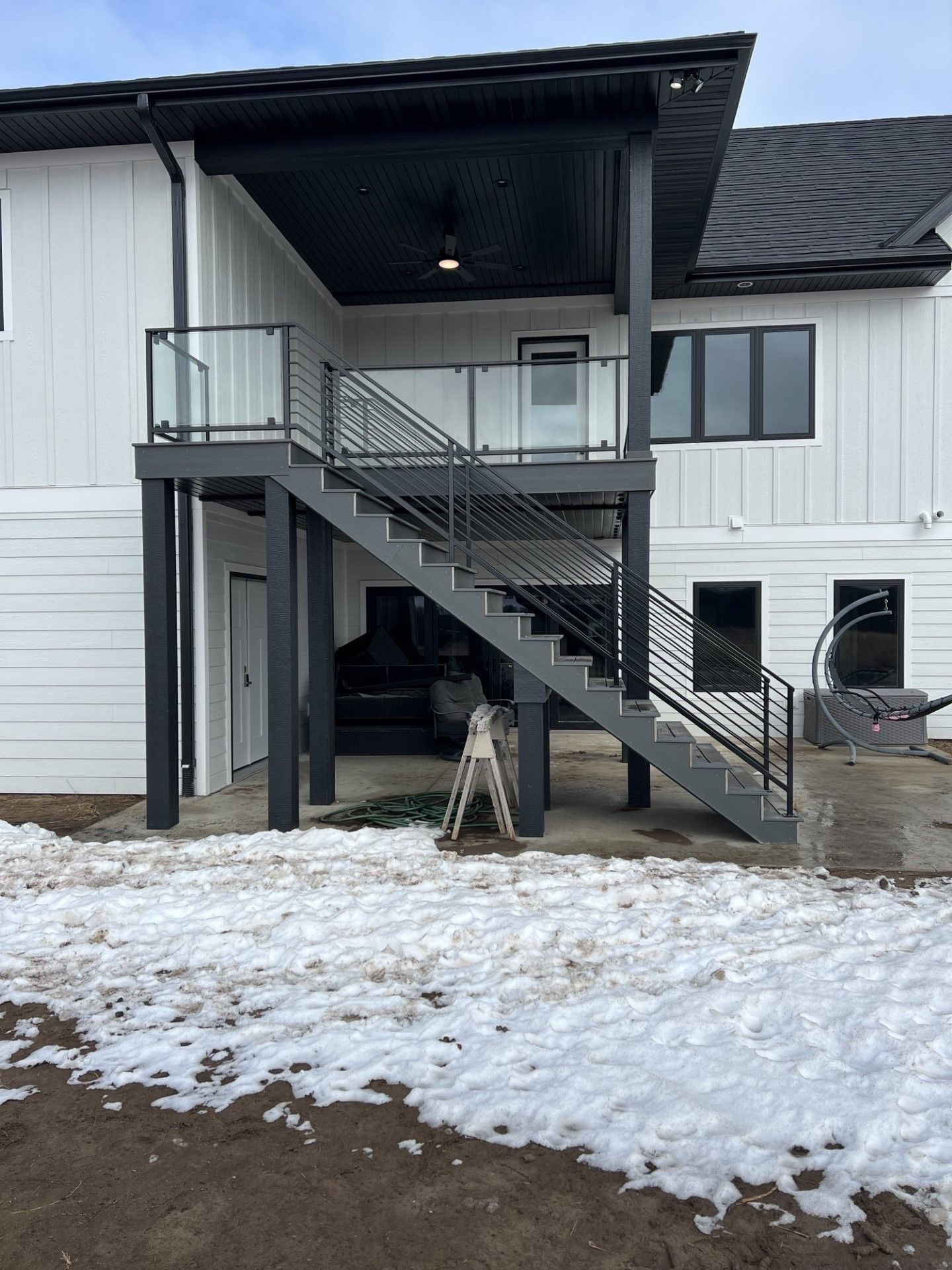 Snowy exterior of a white building with a covered metal staircase and second-floor balcony