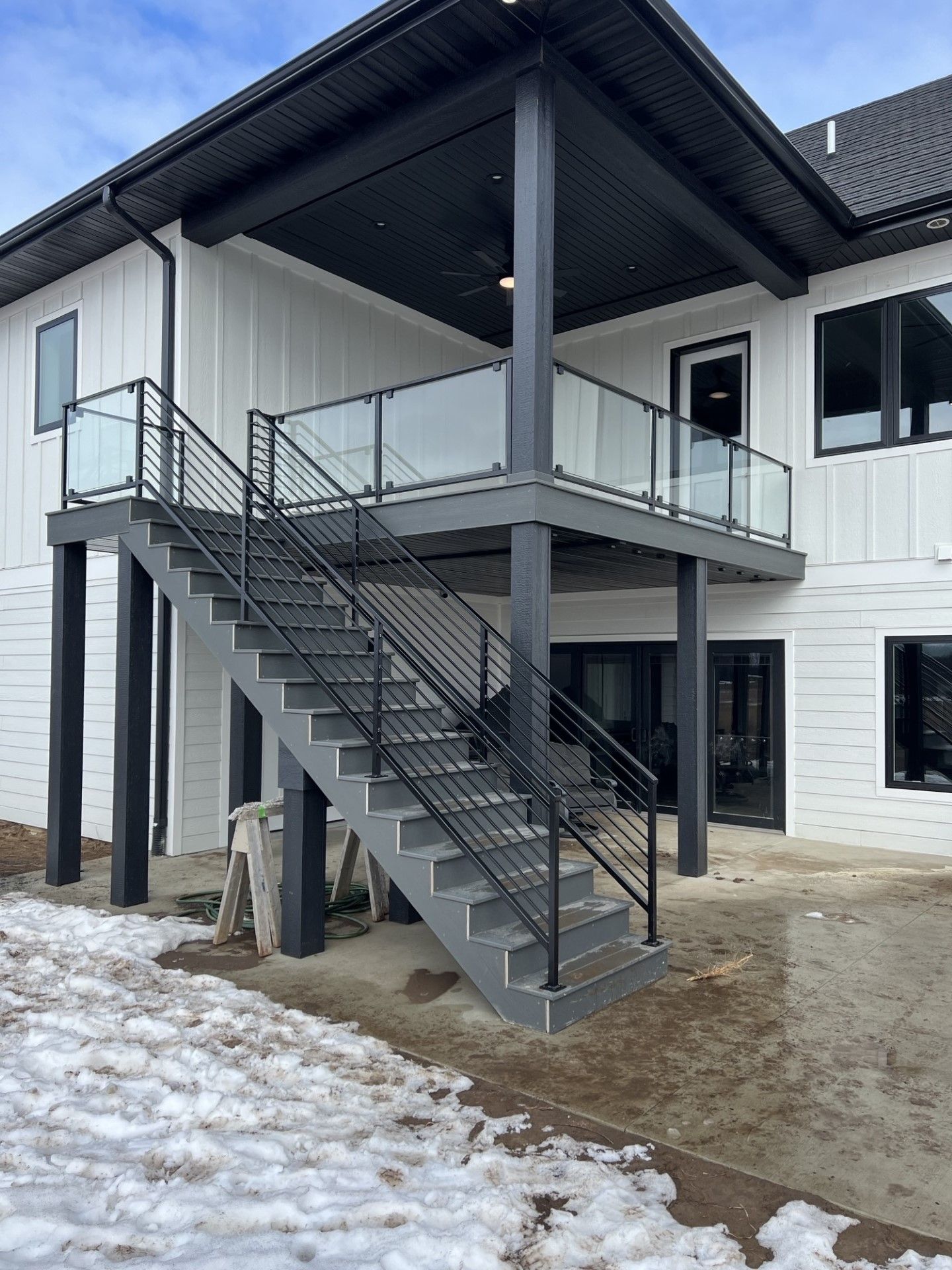 Exterior metal staircase leading to a second-floor entrance on a white building with snow on the ground