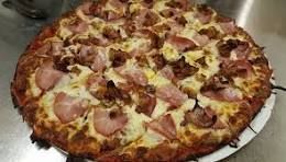 A pizza with a lot of toppings on it is sitting on a table.