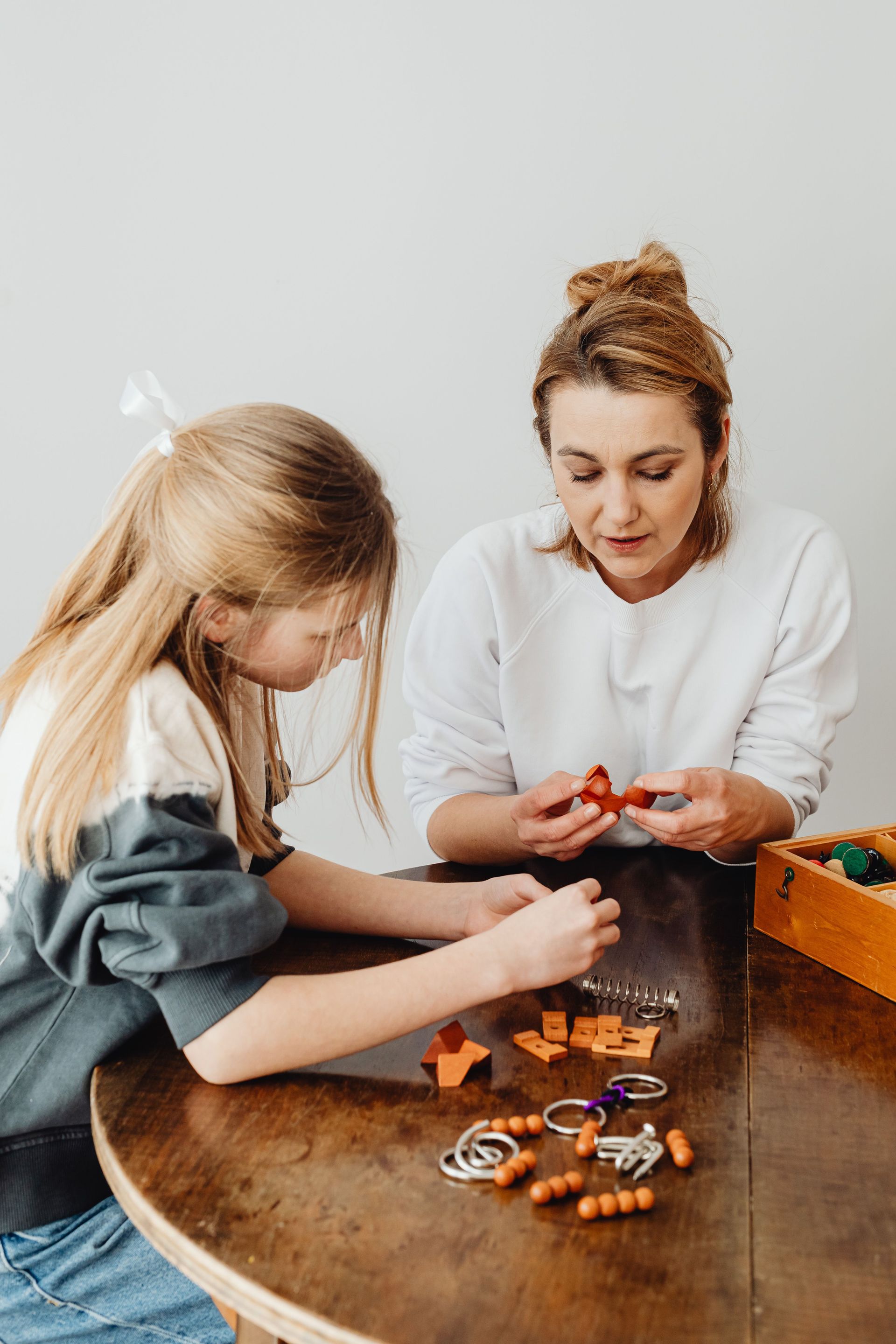 Two people assembling small orange craft pieces at a wooden table