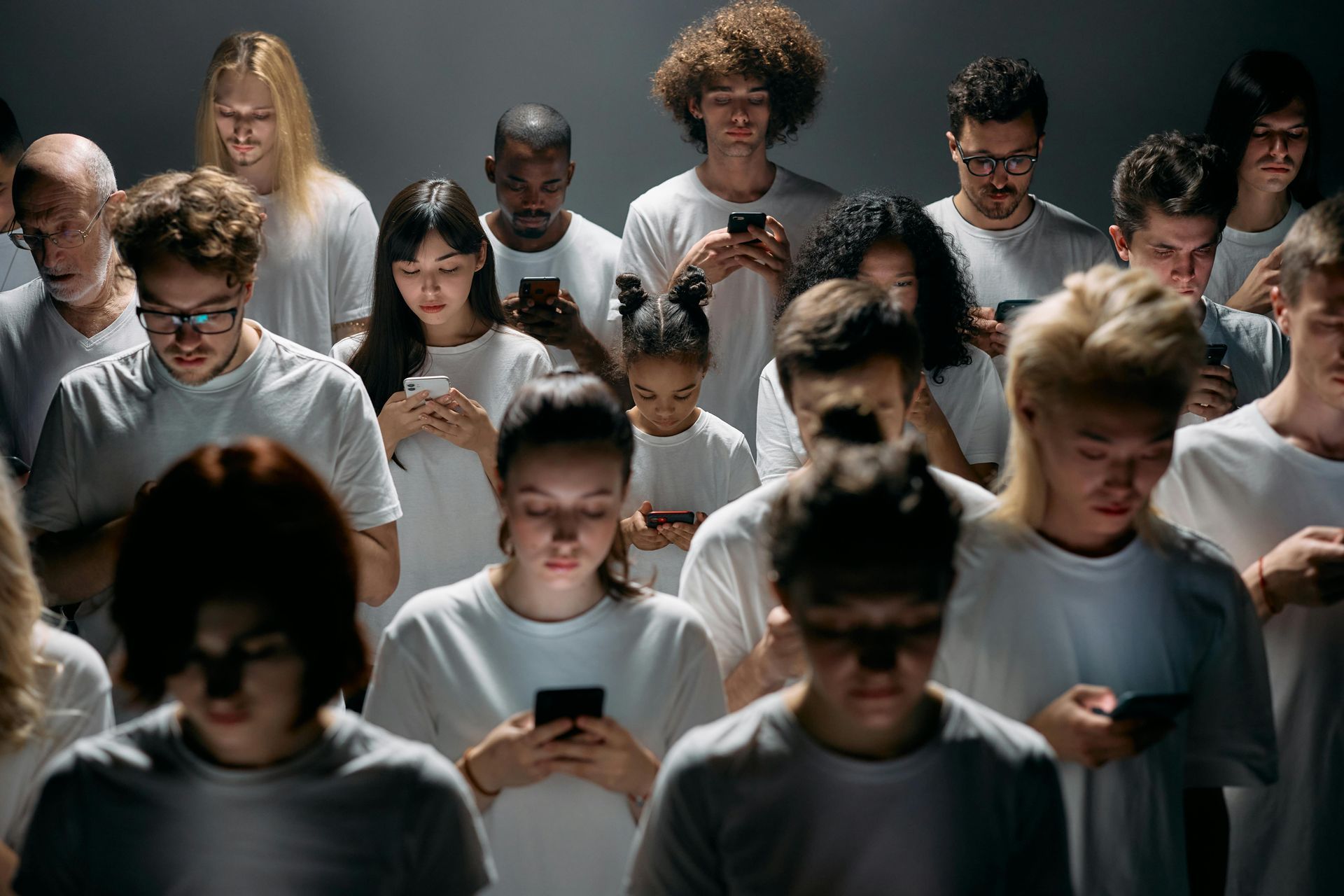 A diverse group of people, including teenagers, standing together while absorbed in their smartphones. A thought-provoking image reflecting social media’s impact on mental health and digital addiction.