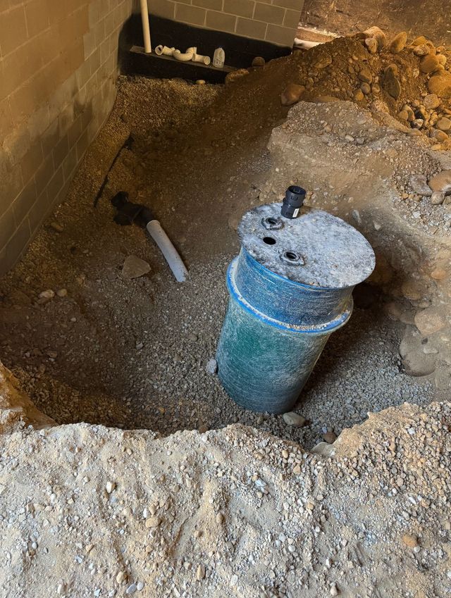 Excavated hole in the ground with a blue pipe and a white capped cylinder amid dirt and rubble