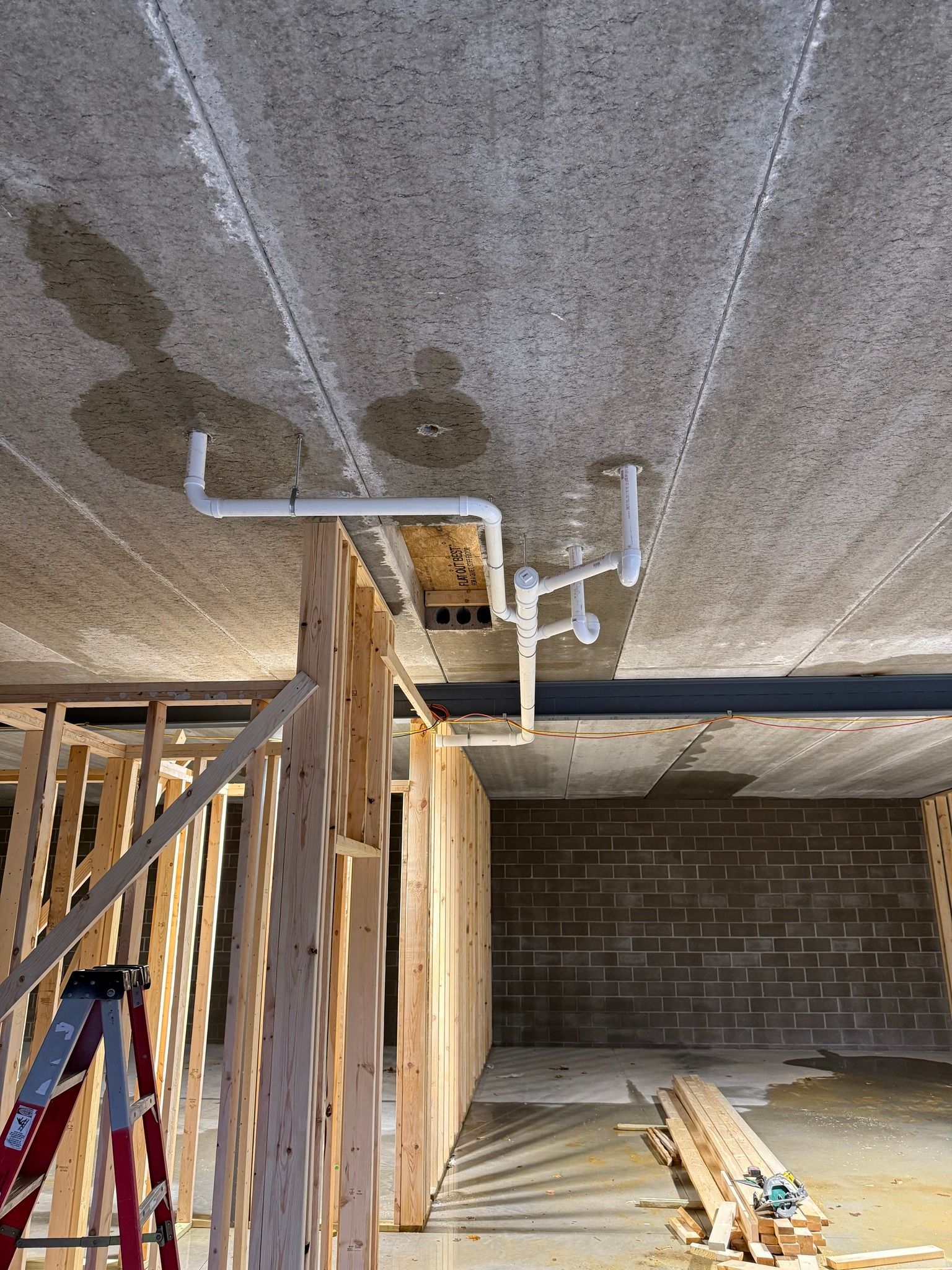 Ceiling-mounted white pipes in an unfinished room under construction
