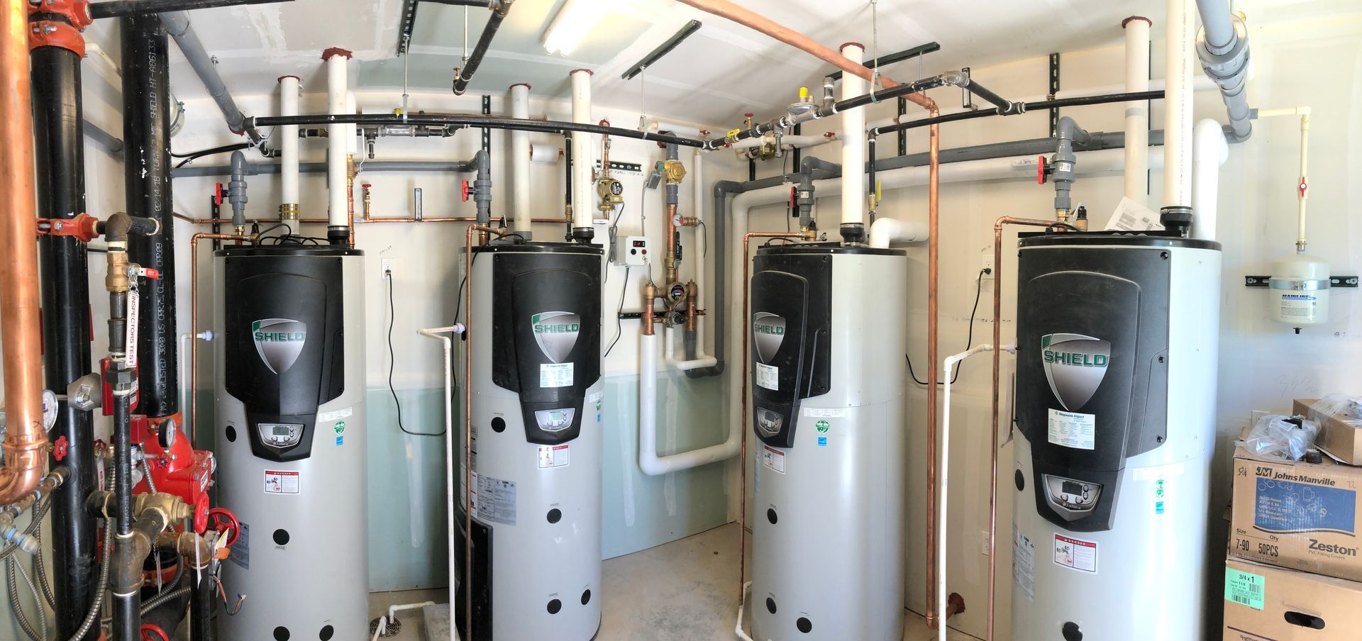 Rows of tall gray industrial tanks and pipes in a mechanical room