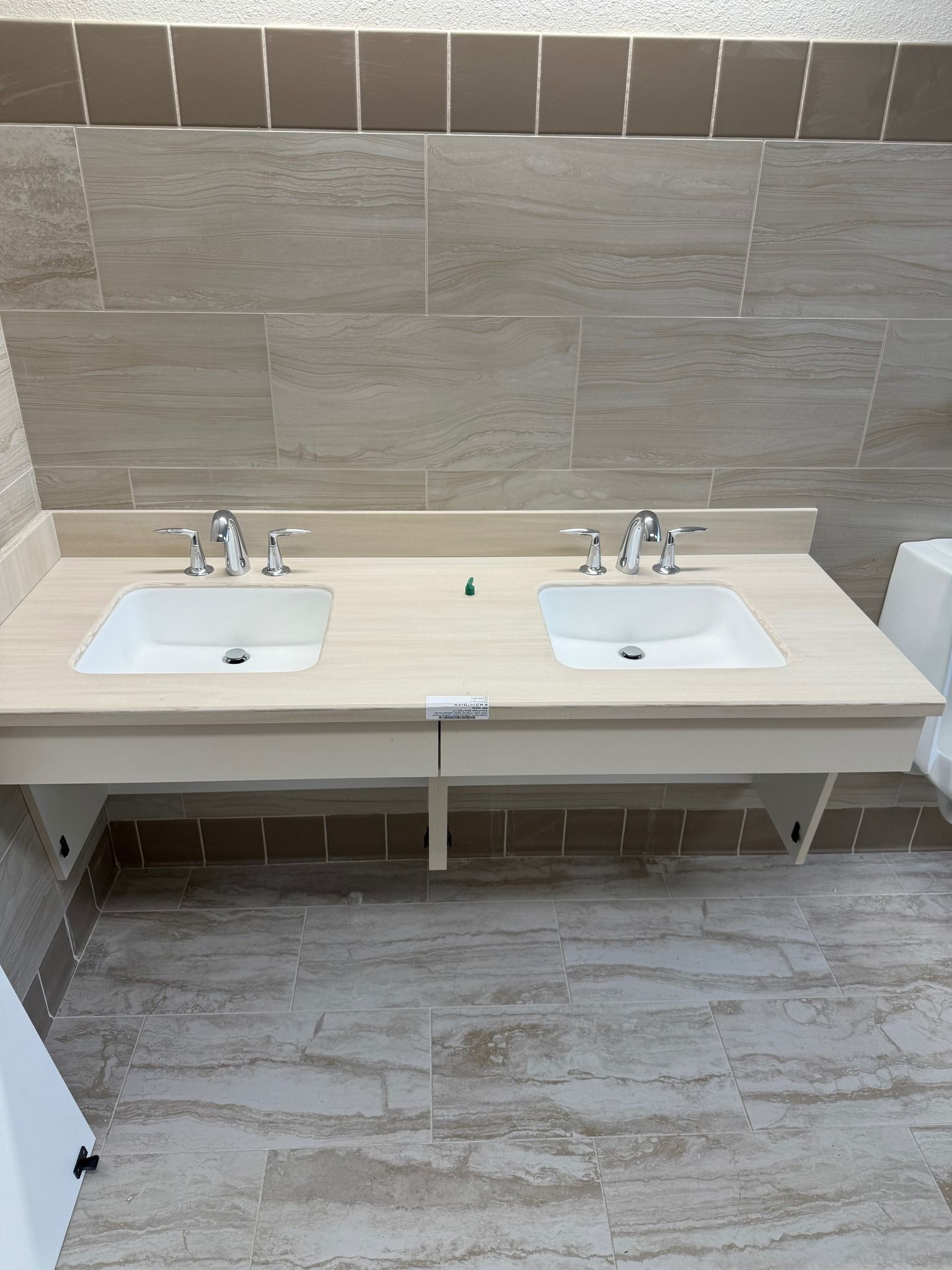 Modern bathroom with two white sinks, mirrors, and gray tiled walls and floor.
