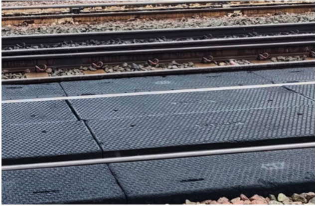 Railway tracks beside a dark textured platform edge with white safety lines