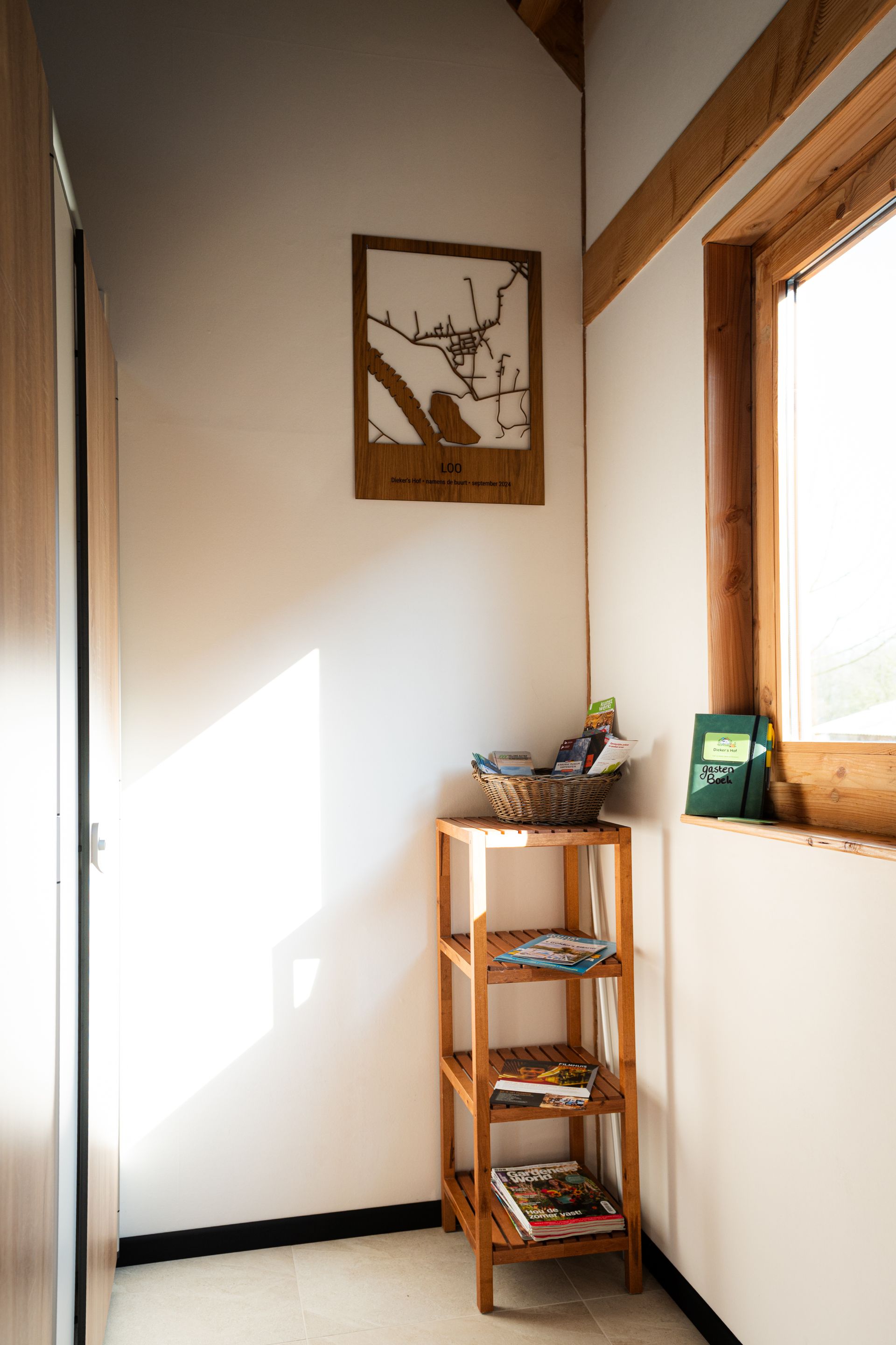 Een hoek van een kamer met een raam met houten kozijn, een kaart en een klein houten plankje.