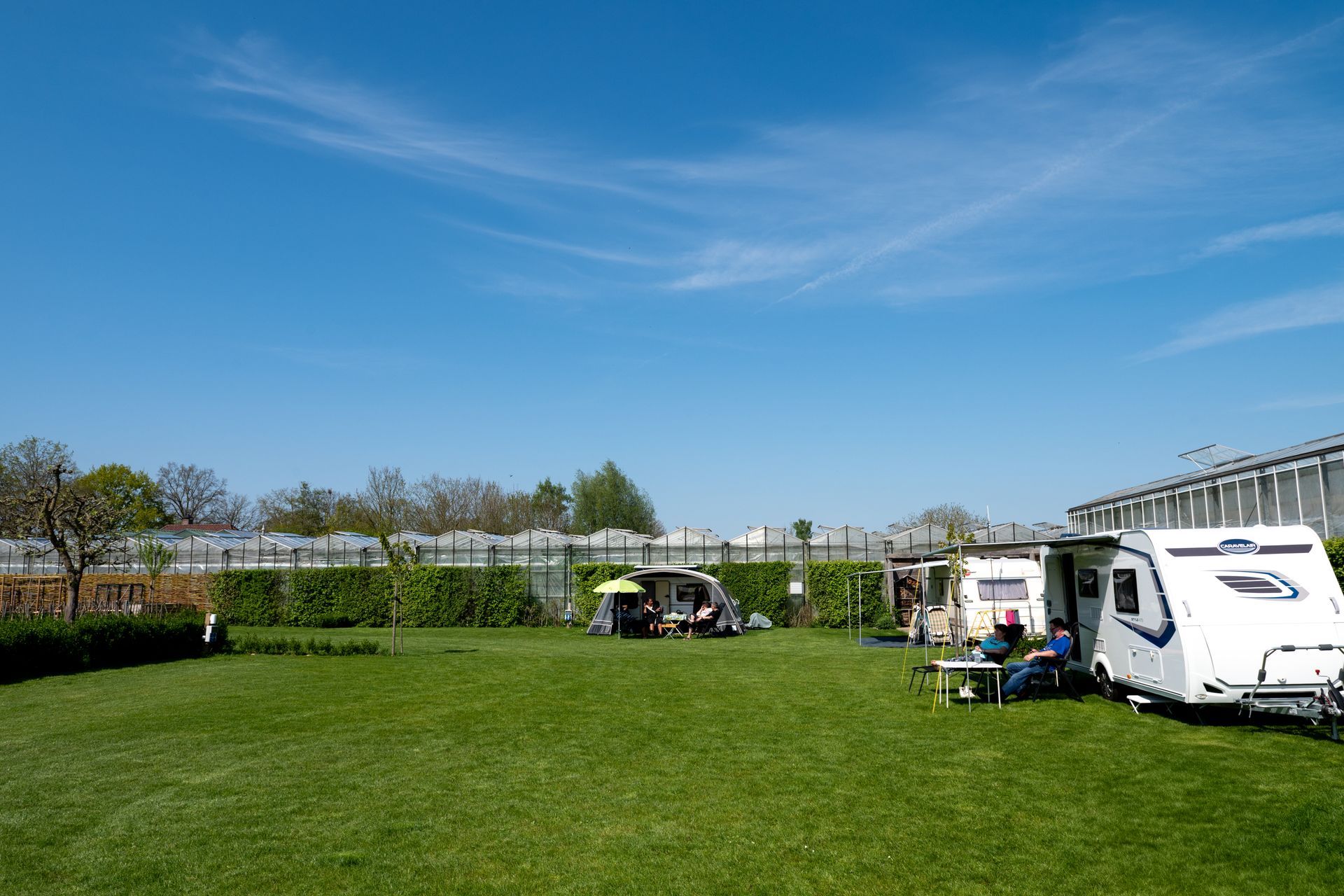 Groen gazon met twee geparkeerde caravans; blauwe lucht.