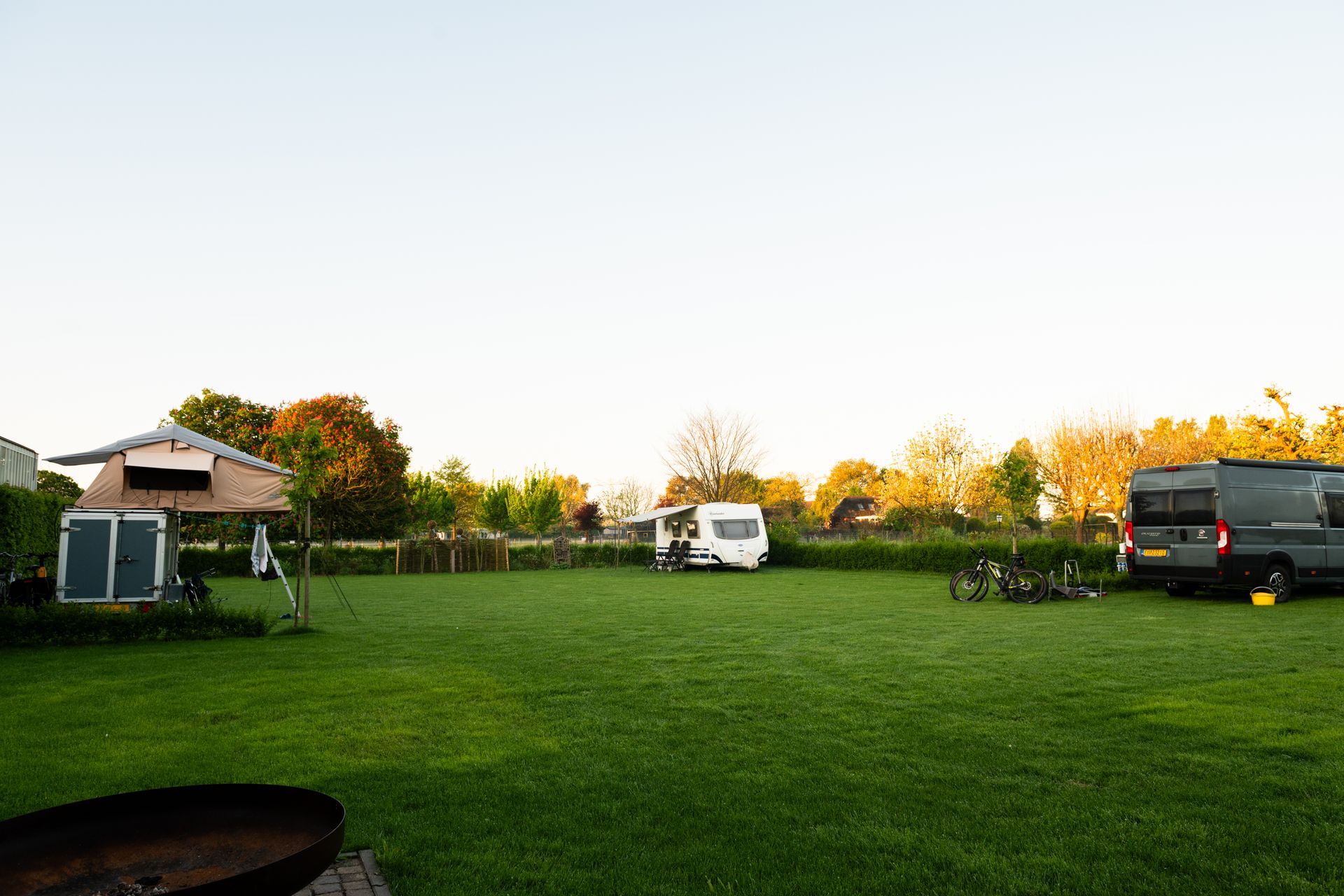 Een grasveldje om te kamperen met een caravan, een busje.