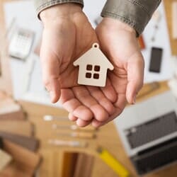 hands holding a wooden model home