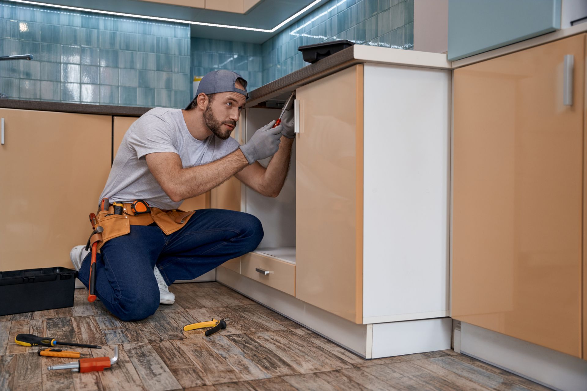 Kitchen remodeling with granite countertop, modern cabinetry, and two pendant lights above island. Handyman performing home remodeling services on kitchen cabinetry