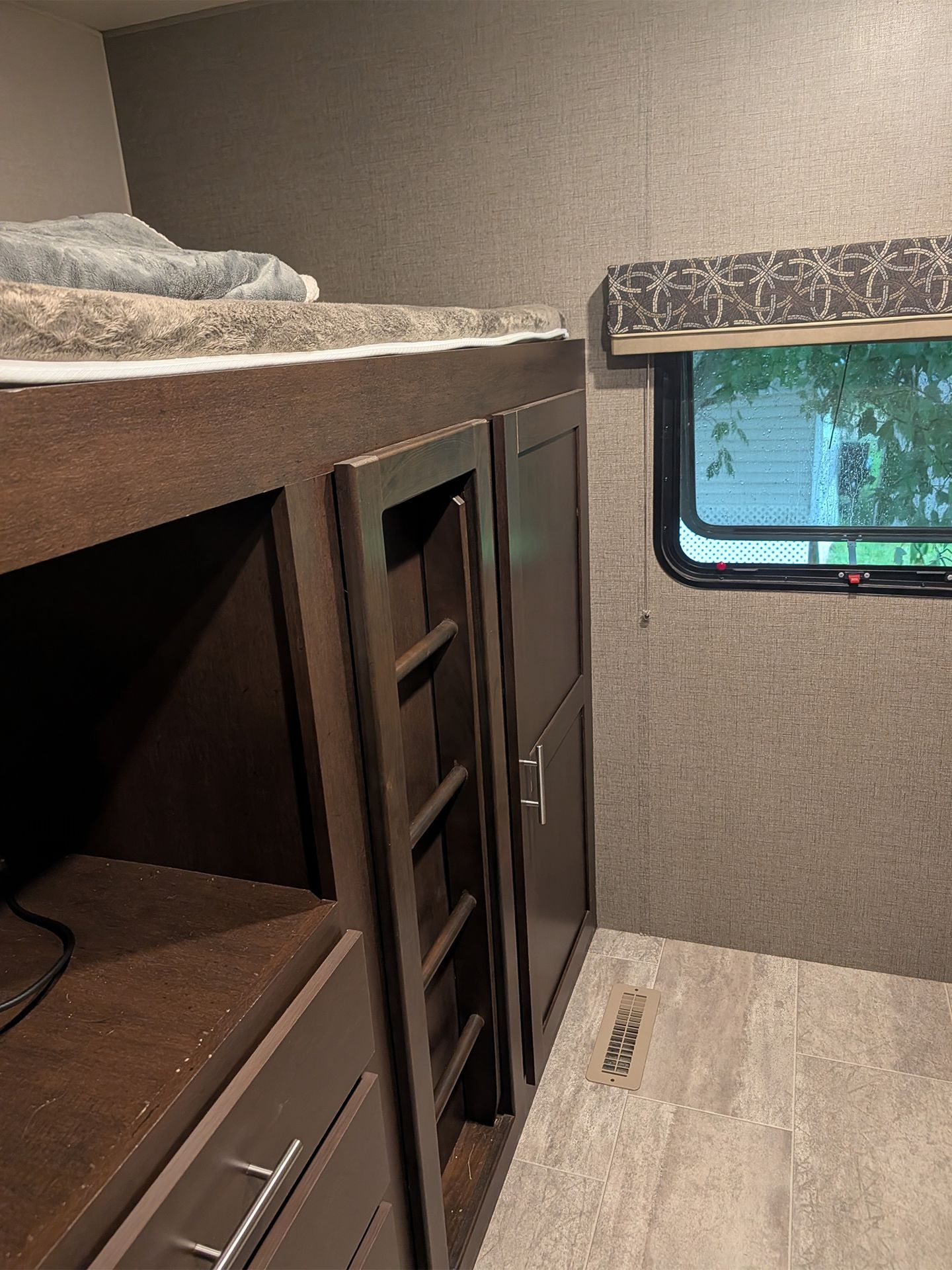 RV bunk room with built-in dark wood cabinets and a small window.