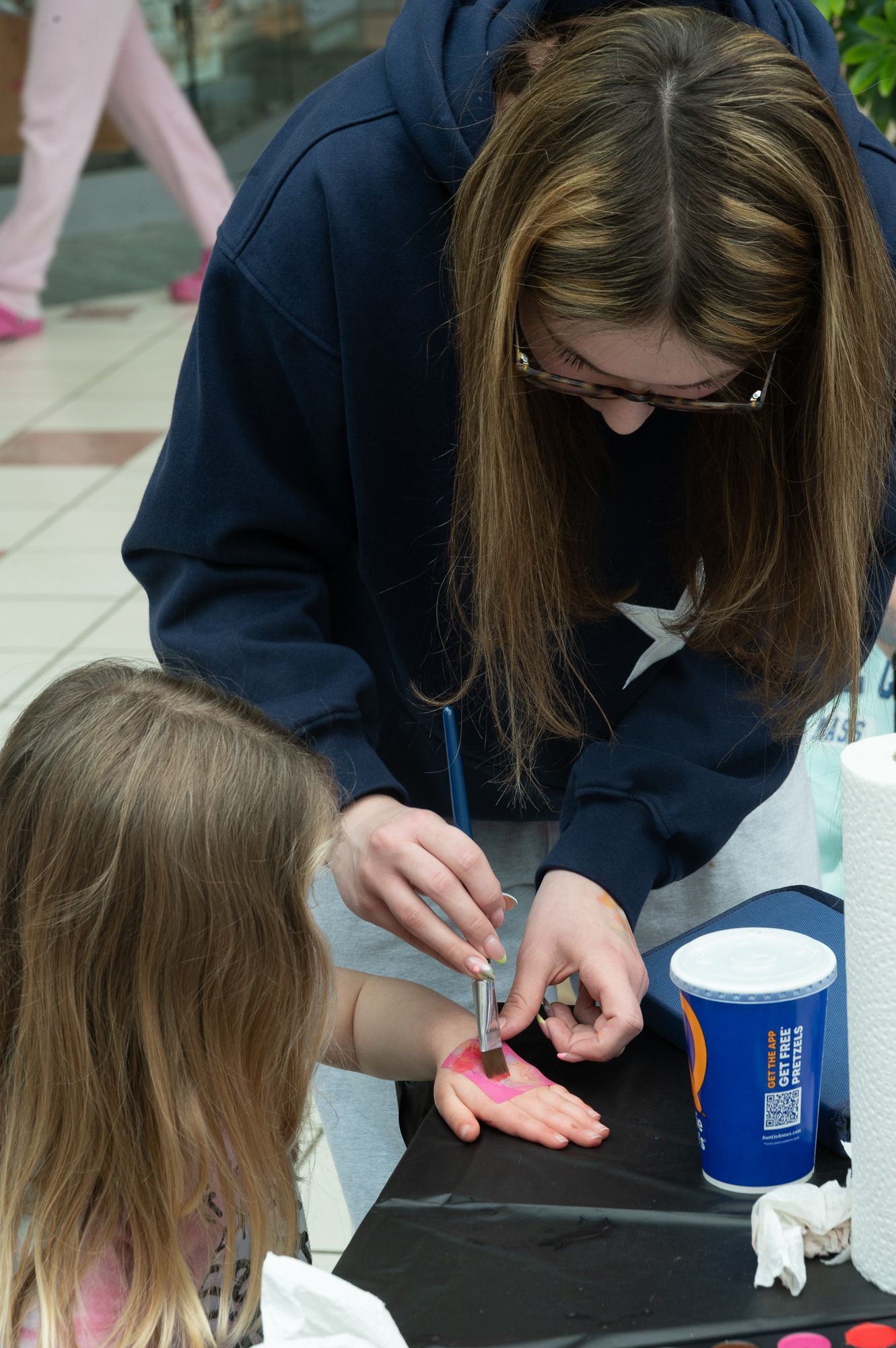 child getting their face painted by a young adult