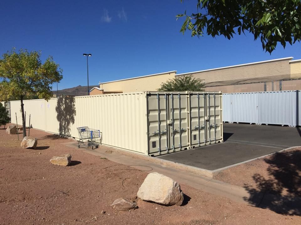 A white shipping container is sitting in front of a building.