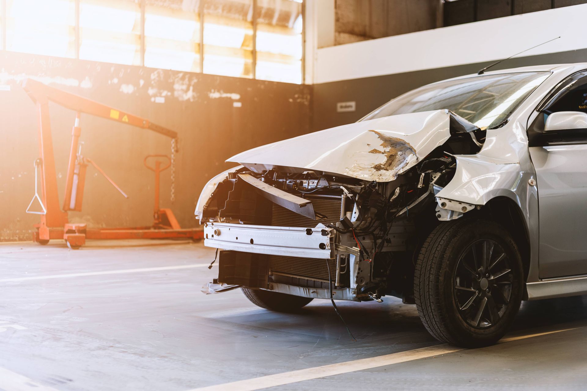 Severely damaged silver car after a crash in a garage or auto repair shop