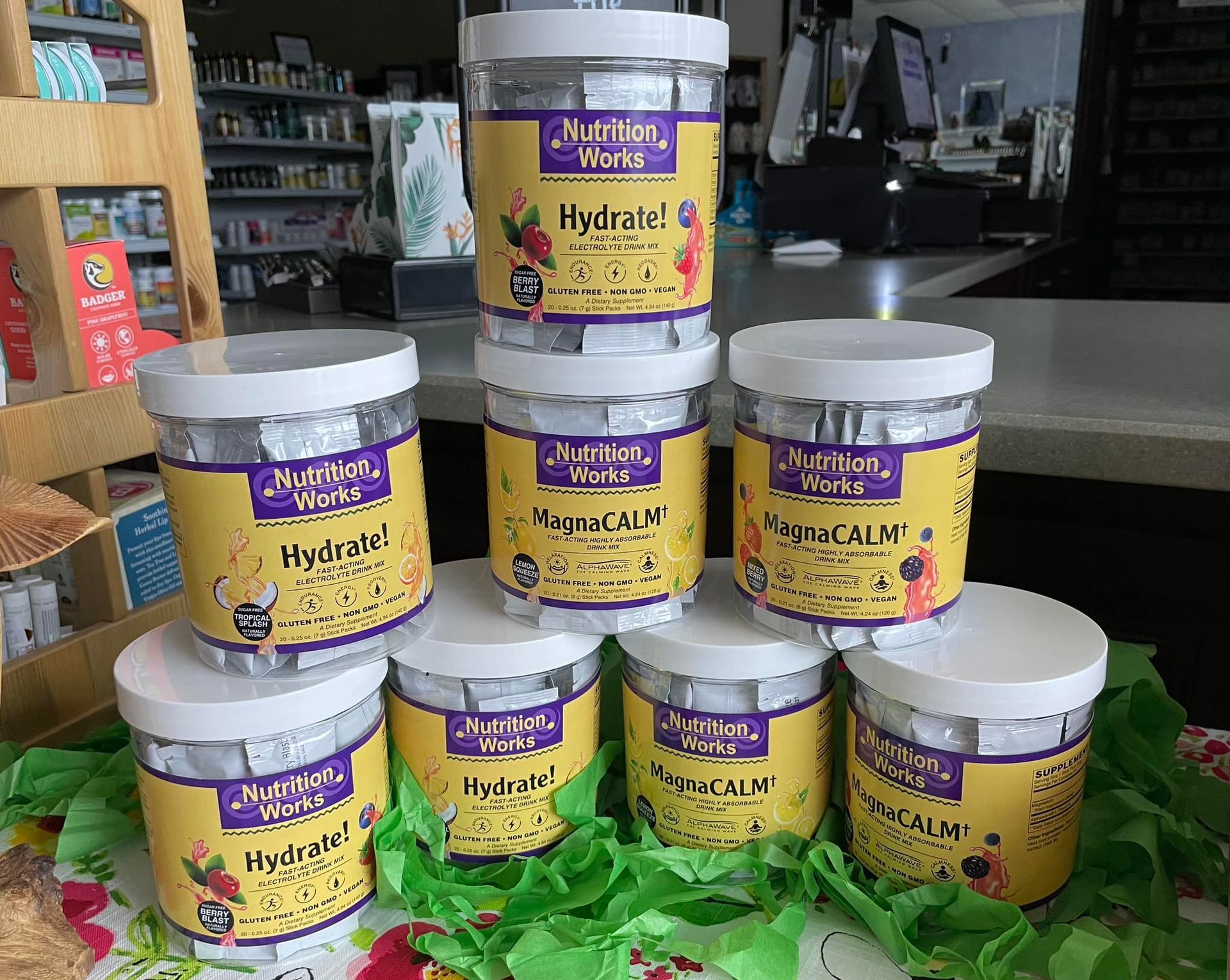 Tubs of Nutrition Works supplements: Hydrate and MindCALM. Stacked on a counter with greenery.