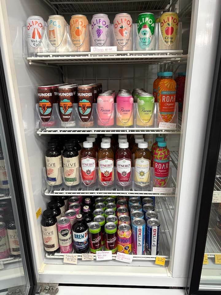 Refrigerator stocked with various canned and bottled beverages; mostly colorful fruit-flavored drinks.