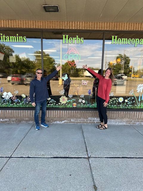 Two people stand in front of a store window with 