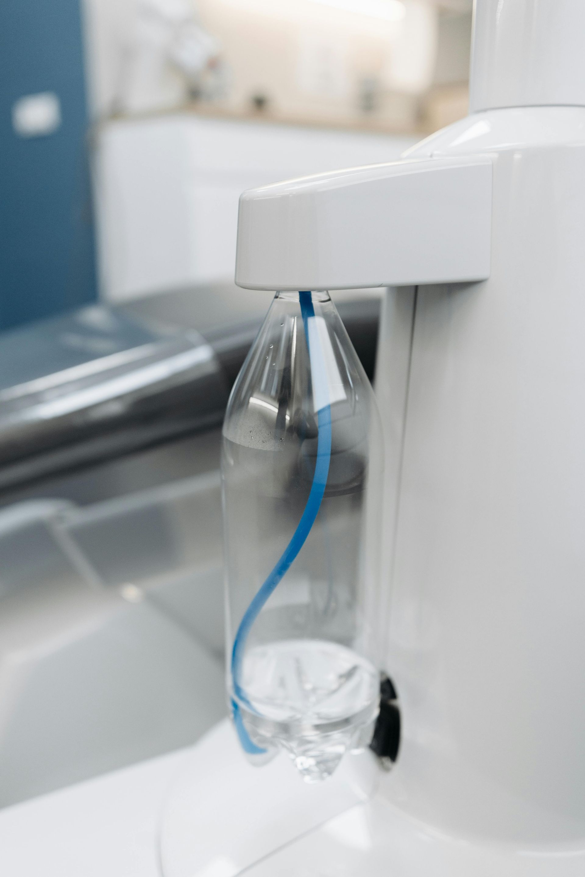 Clear water bottle with blue tubing attached to white medical equipment.
