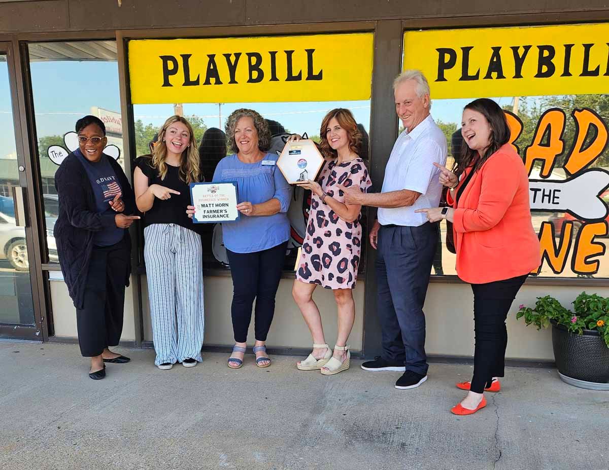 People holding a key and plaque in front of a theater with 