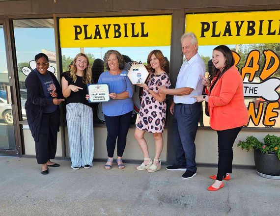 People holding plaque and key outside a building with 
