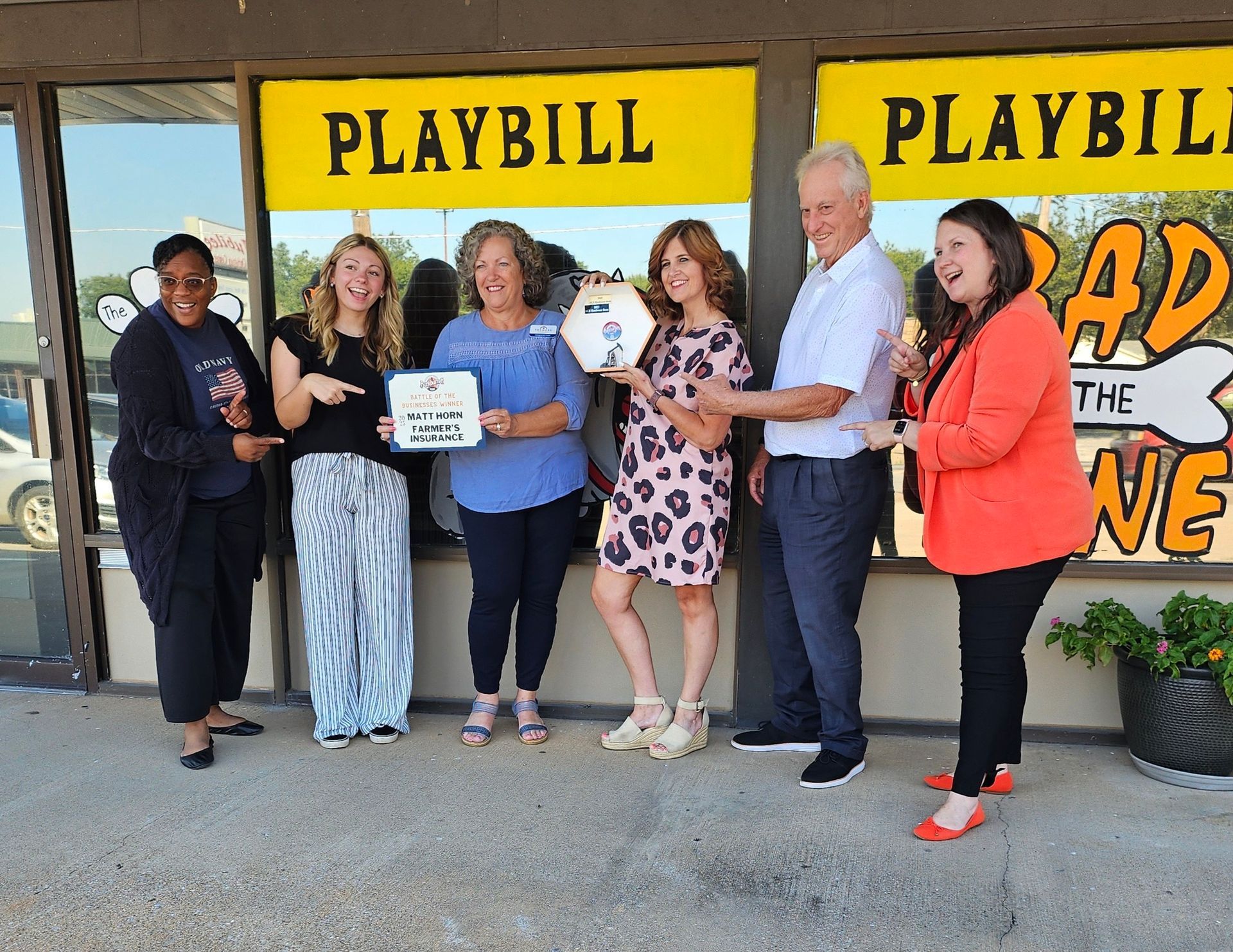 Group of people holding an award, standing in front of a theater with