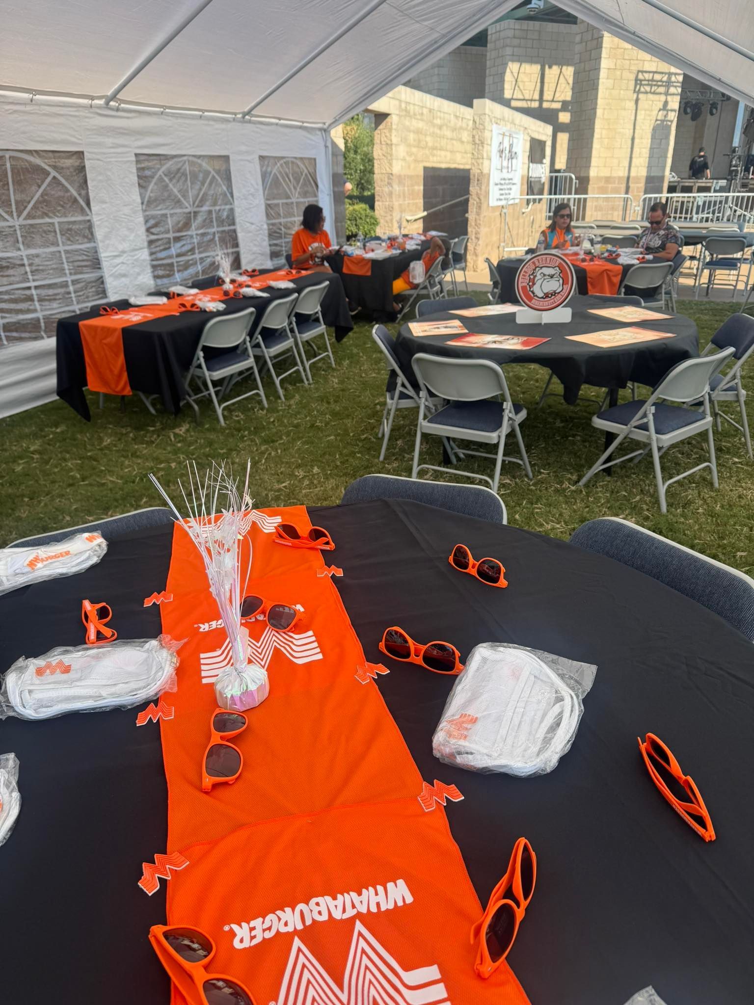Tables with Whataburger decor under a tent for an outdoor event. Orange and black color scheme.