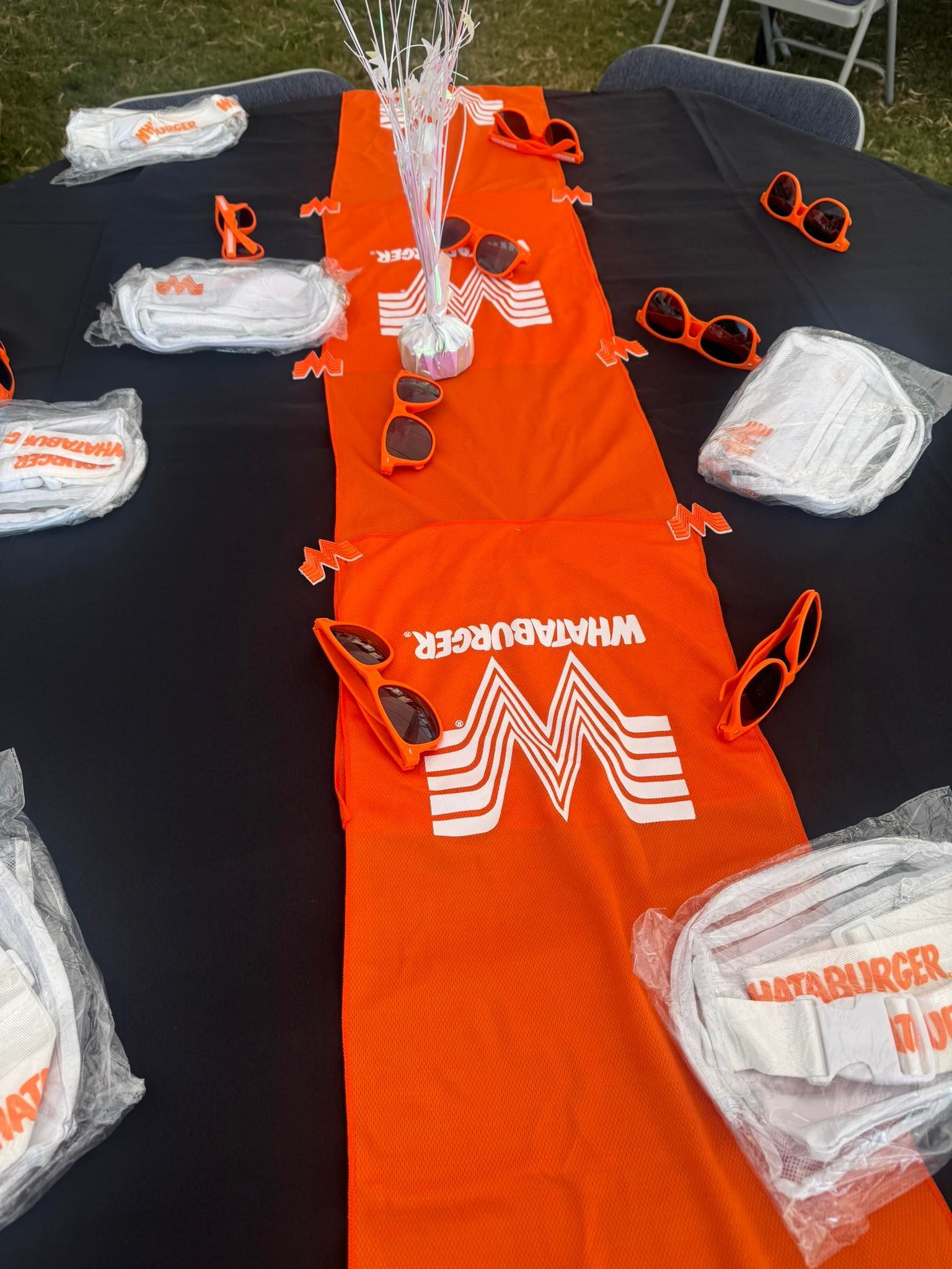 A table decorated with orange Whataburger theme. Includes a runner, sunglasses, and wrapped plates.