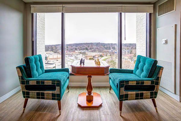 A living room with two chairs and a table in front of a large window.