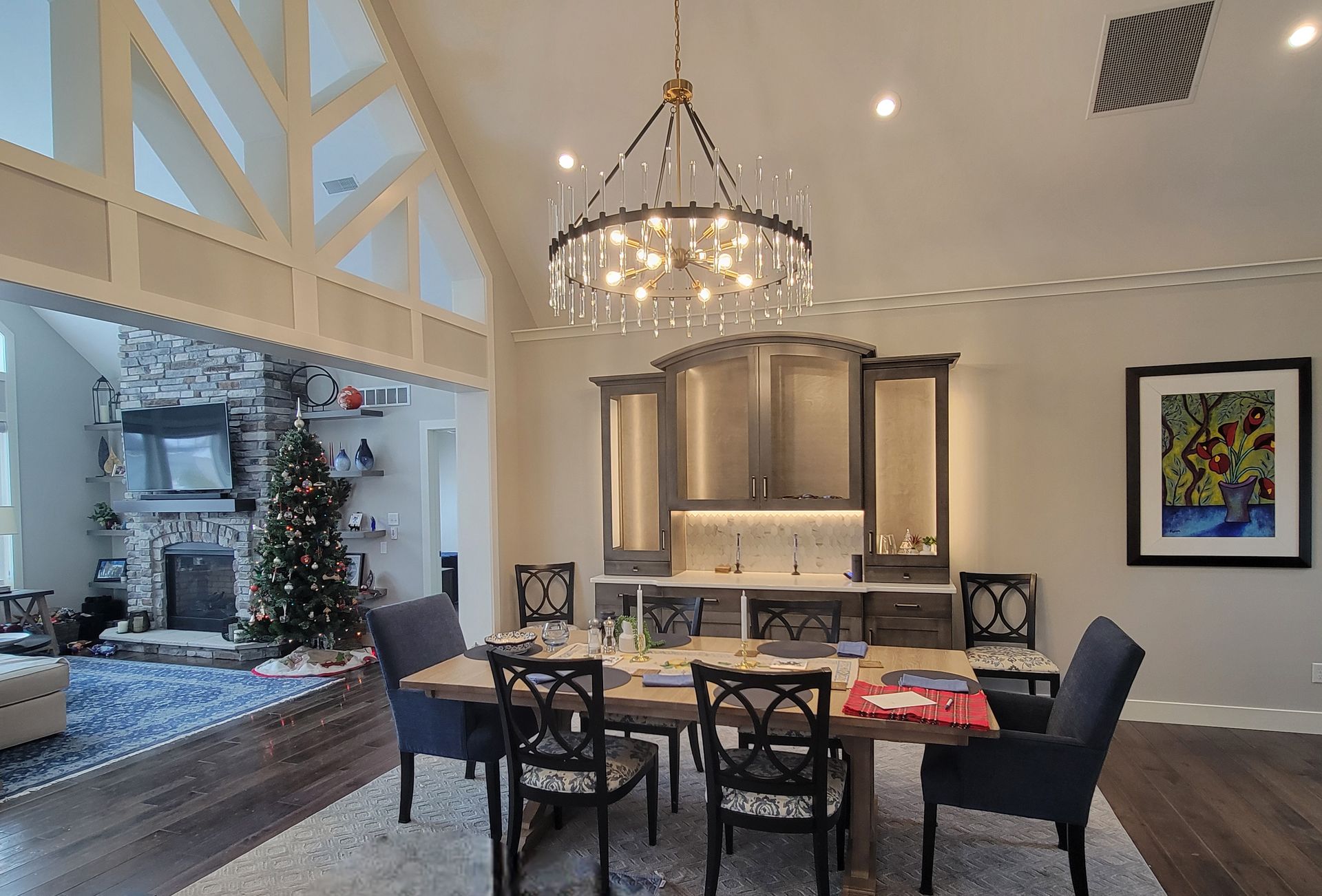 A formal dining room featuring a wooden table, dark upholstered chairs, a crystal chandelier, and a built-in buffet.
