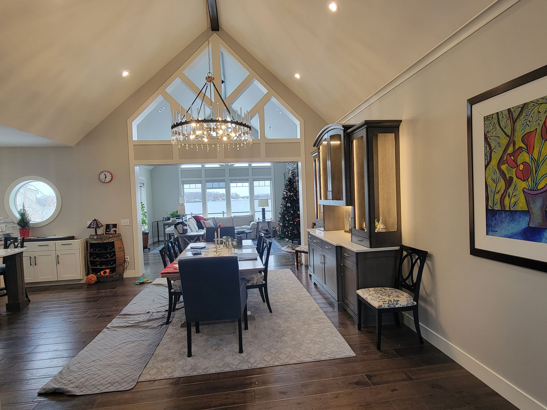 Spacious dining area with a high-vaulted ceiling, chandelier, dark wood floors, a dining table, and built-in cabinetry.