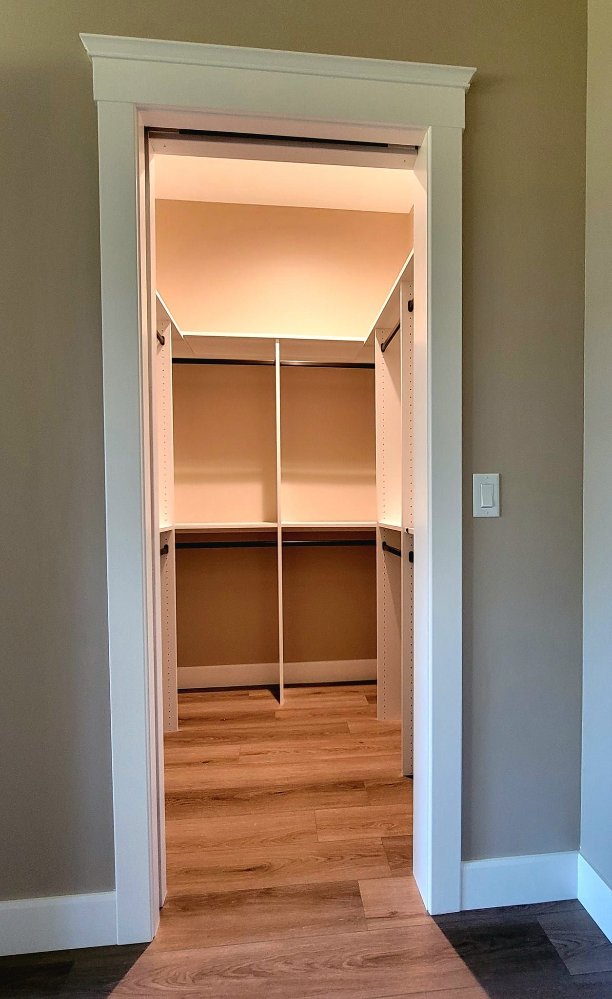 An open doorway leads into a walk-in closet with white wooden shelving and light-colored wood flooring.