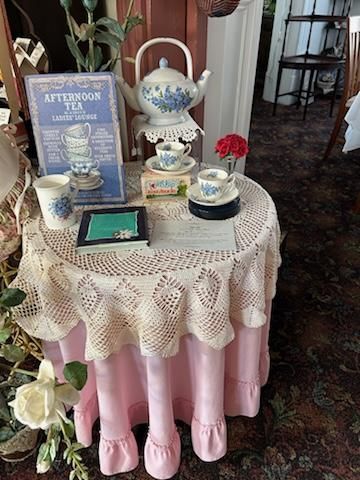 A table with a pink tablecloth and a tea set on it.