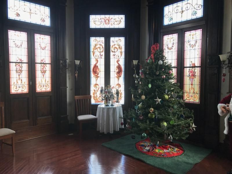 A christmas tree is in a room with stained glass windows.