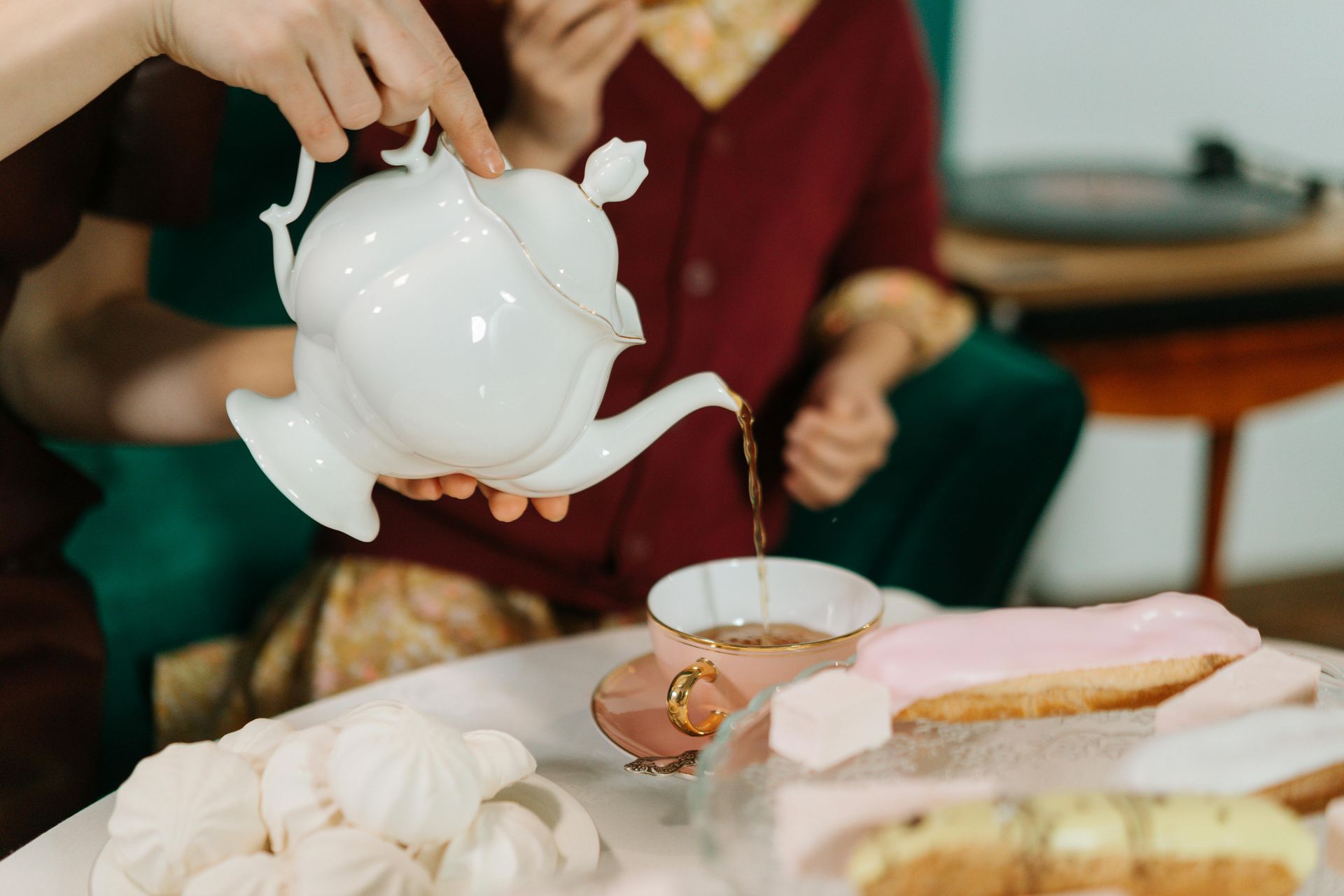 A person is pouring tea into a cup at a tea party.